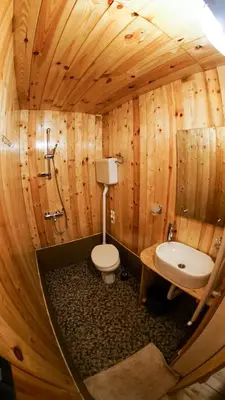 a wooden bathroom with a toilet and a sink at Golema Reka in Crni Vrh