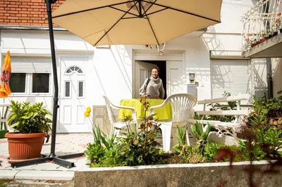 a woman sitting at a table with an umbrella at Apartmani Didić in Soko Banja