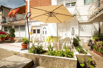 a patio with an umbrella and chairs and plants at Apartmani Didić in Soko Banja