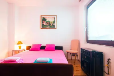 a bedroom with a bed with pink pillows and a window at Apartmani Slavica in Jagodina