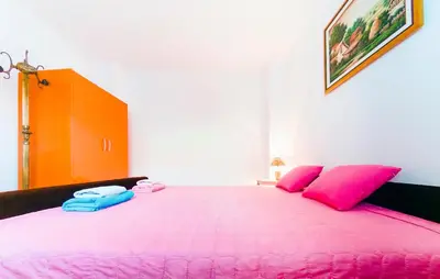 a bedroom with a large pink bed with pink pillows at Apartmani Slavica in Jagodina