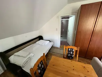 a small bedroom with a bed and a wooden table at Apartments and Rooms Vicko in Brzeće