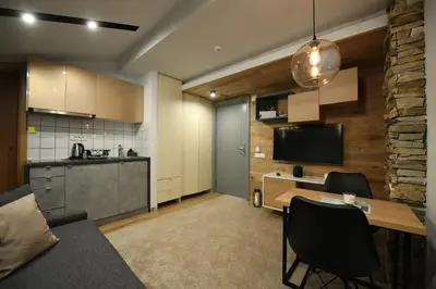 a kitchen and a living room with a table and chairs at Apartmani Marija in Kopaonik