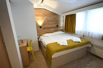 a bedroom with a bed and a desk and a window at Apartmani Marija in Kopaonik
