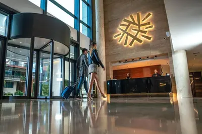 two people walking in a lobby with their luggage at Hotel Tonanti in Vrnjačka Banja