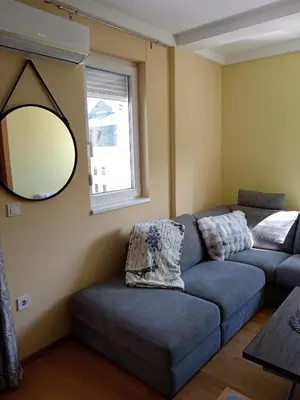 a living room with a blue couch and a mirror at Apartmani Pezerović in Soko Banja