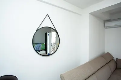 a mirror hanging on a white wall in a living room at Apartmani Pezerović in Soko Banja
