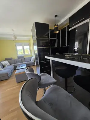 a kitchen and living room with chairs and a table at Apartmani Pezerović in Soko Banja
