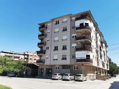 a tall apartment building with cars parked in front of it at Cozy and Lovely Appartment in Jagodina