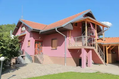 a pink house with stairs and a balcony at Vila Viktori in Pirot