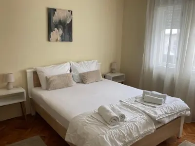 a bedroom with a large white bed with towels on it at Haus Apartman Zaječar M&L in Zaječar
