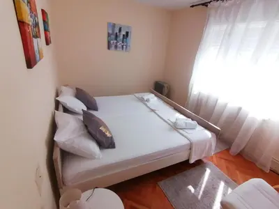 a small bed in a room with a window at Haus Apartman Zaječar M&L in Zaječar
