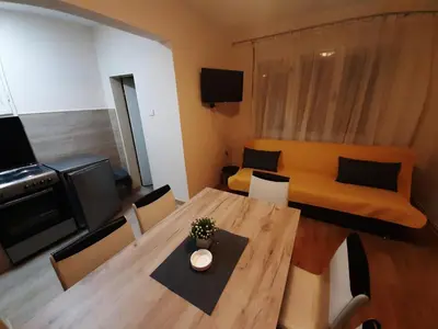 a living room with a wooden table and a couch at Haus Apartman Zaječar M&L in Zaječar