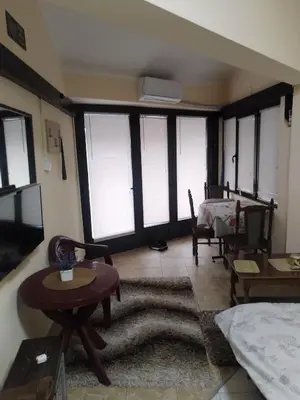 a living room with windows and a bed and a table at TREF 1 in Soko Banja