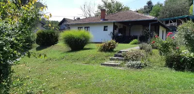 a small white house with a yard with plants at Apartman Kućica za odmor , Drašković in Vrnjačka Banja