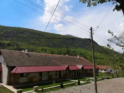 a building with red roofs with mountains in the background at Sobe Gmitrovic in Rtanj