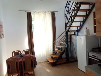 a living room with a staircase and a room with a suitcase at Apartmani MIDUĆI in Vrnjačka Banja