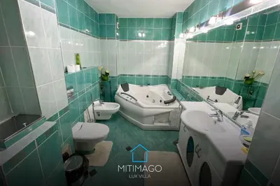 a green tiled bathroom with a sink and a toilet at Lux Villa Mitimago in Niš