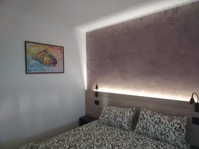 a bedroom with a bed and a painting on the wall at Apartmani Pause in Niš