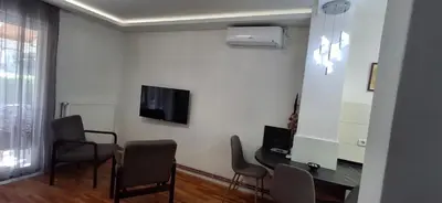 a living room with chairs and a table and a tv at Apartmani Pause in Niš