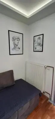 a bedroom with a bed and three pictures on the wall at Apartmani Pause in Niš