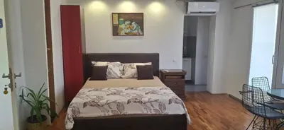 a bedroom with a bed and a table in a room at Apartmani Pause in Niš