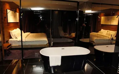 a bathroom with a bath tub and a bed at Ambasador Hotel in Niš