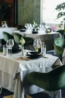 a couple of tables with plates and glasses on them at Ambasador Hotel in Niš