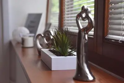 two metal sculptures on a window sill next to a plant at Apartman LM in Vrnjačka Banja