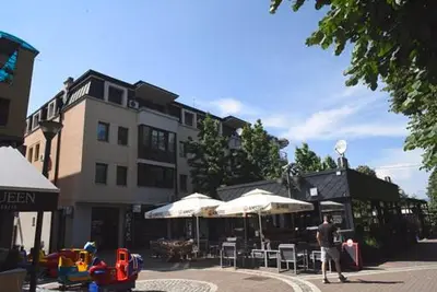 a man standing in front of a building with umbrellas at Apartman LM in Vrnjačka Banja