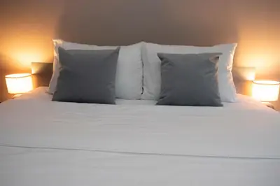 a white bed with two pillows and two lamps at Venus in Niš