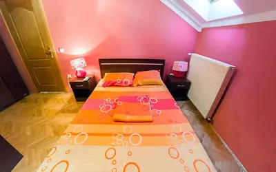 a bedroom with two beds with orange and pink walls at Apartmani Bellini in Soko Banja