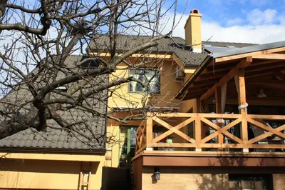 a house with a wooden balcony and a roof at Guesthouse Silvani in Kruševac
