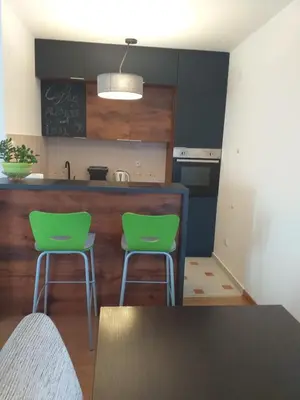 a kitchen with two green chairs and a table at Sanjar in Vrnjačka Banja