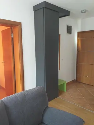 a living room with a gray couch and a door at Sanjar in Vrnjačka Banja