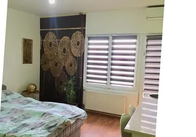 a bedroom with a bed and a window with blinds at DUŠICA APARTMANI in Jagodina
