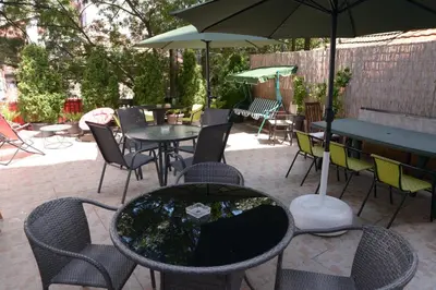 a patio with tables and chairs and an umbrella at Guest House GOLDEN COIN in Niš
