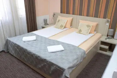 two beds in a hotel room with towels on them at Guest House GOLDEN COIN in Niš