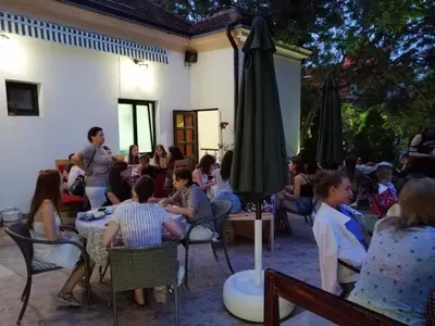 a group of people sitting at tables in a patio at Guest House GOLDEN COIN in Niš