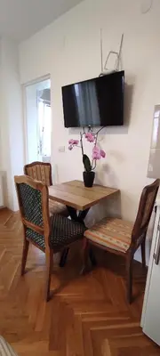 a dining room table with two chairs and a television on the wall at Vila Sentić in Vranje