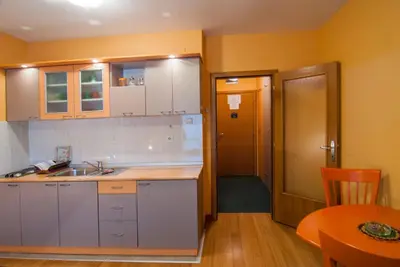 a kitchen with a sink and a table and a door at Apartments Raj in Vrnjačka Banja