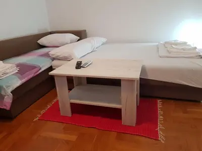 a bed with a wooden table next to a bed with a bedskirts at Studio Dorna in Vrnjačka Banja