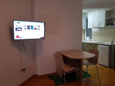 a kitchen with a table and a flat screen tv on the wall at Studio Dorna in Vrnjačka Banja