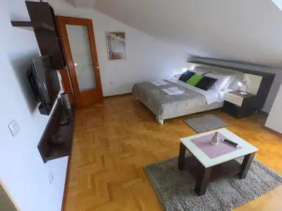 a bedroom with a bed and a table and a tv at Apartman ZENIT in Vrnjačka Banja