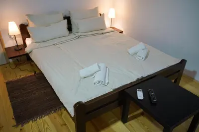 a large bed with slippers and a remote control on it at Epicenter in Niš