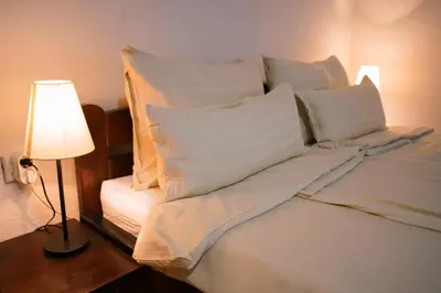 a bed with white sheets and pillows next to a lamp at Epicenter in Niš