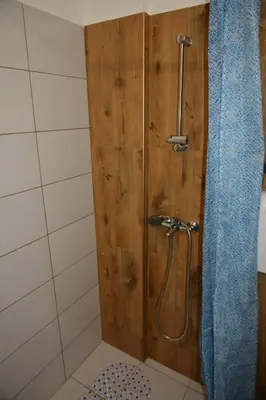 a bathroom with a shower with a blue shower curtain at VIV apartment 1 in Niš