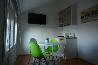 a small kitchen with a table and green chairs at VIV apartment 2 in Niš