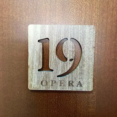 a wooden sign on a wall with the number opera at Lux Apartman 'Opereta' A-19 in Vrnjačka Banja