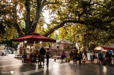 a group of people standing around a food stand with an umbrella at Sokobanja central park APT with mountain view balcony in Soko Banja